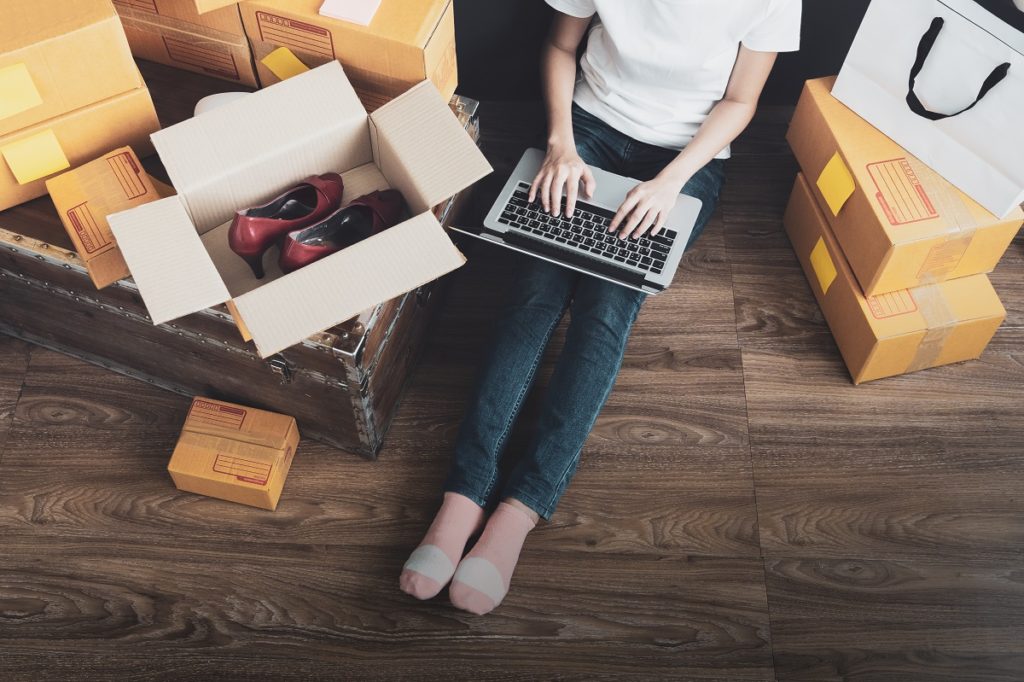 woman checking online orders surrounded by boxes